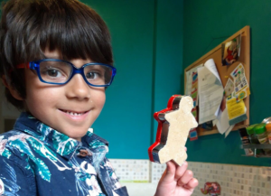 Robi smiling and holding up a ginger bread man biscuit.