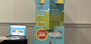 image shows CAN pull-up banner next to a table with a laptop on it