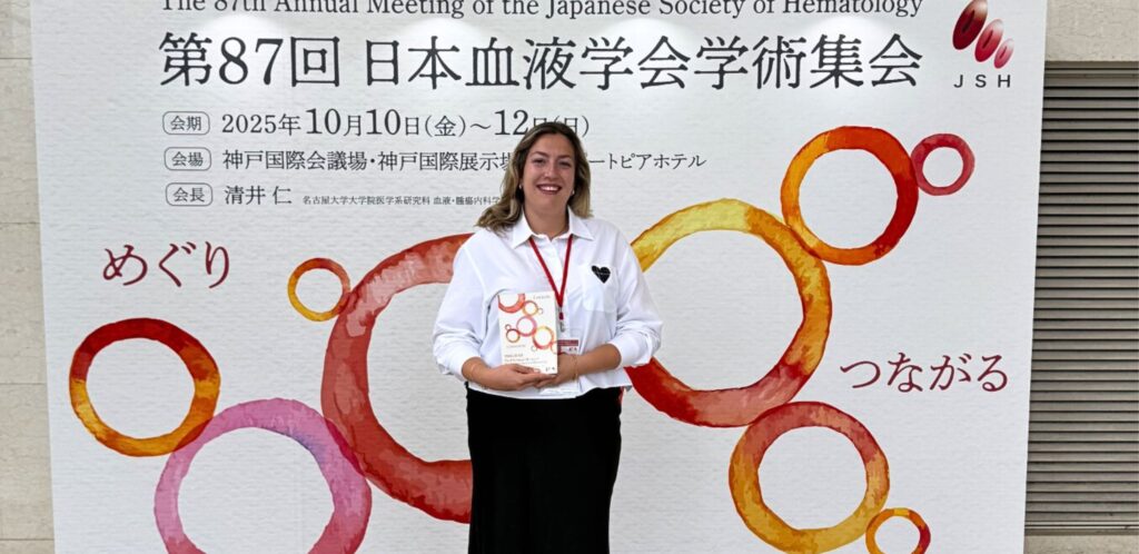 Sanja standing in front of a sign with Japanese writing on